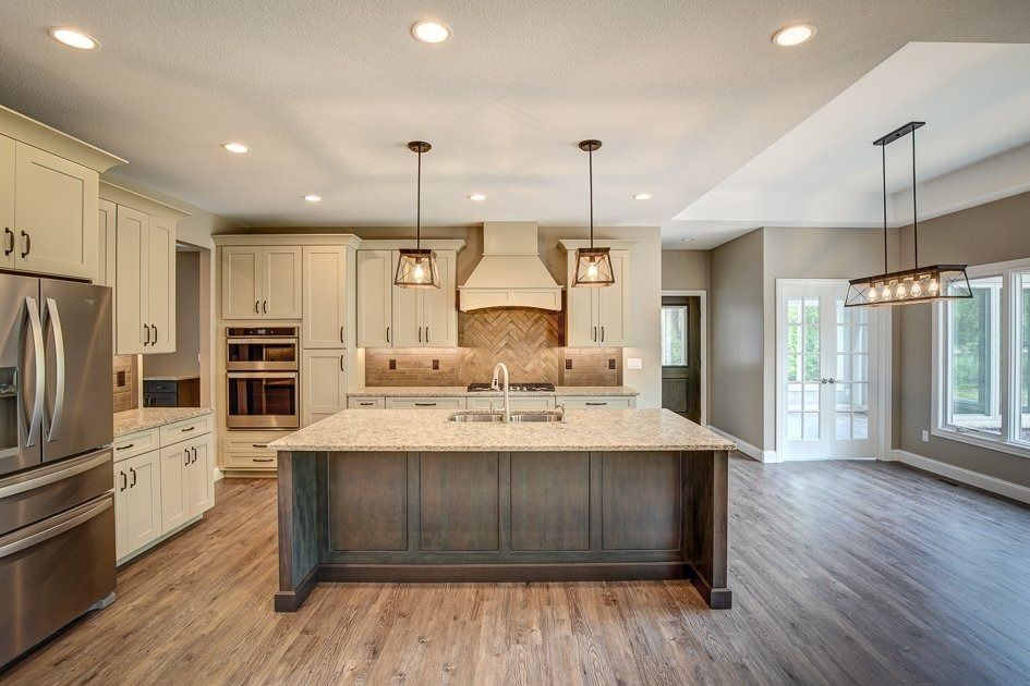 Spacious kitchen with large island, light cabinets, and stainless steel appliances. Hardwood floors and pendant lights.
