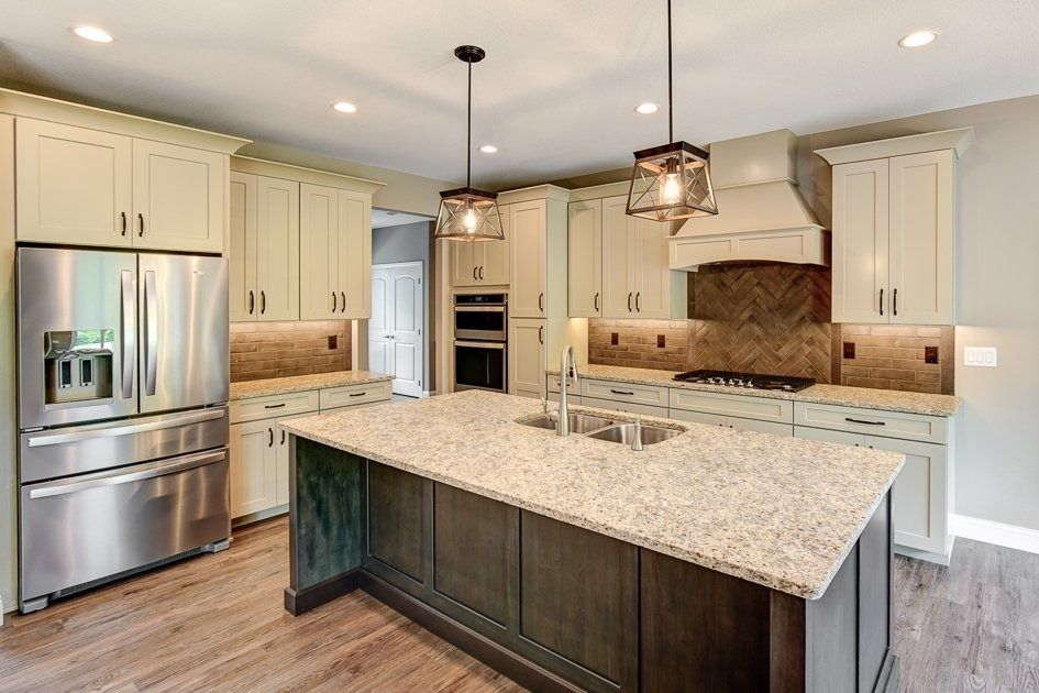 Spacious kitchen with cream cabinets, stainless steel appliances, and a granite countertop island.