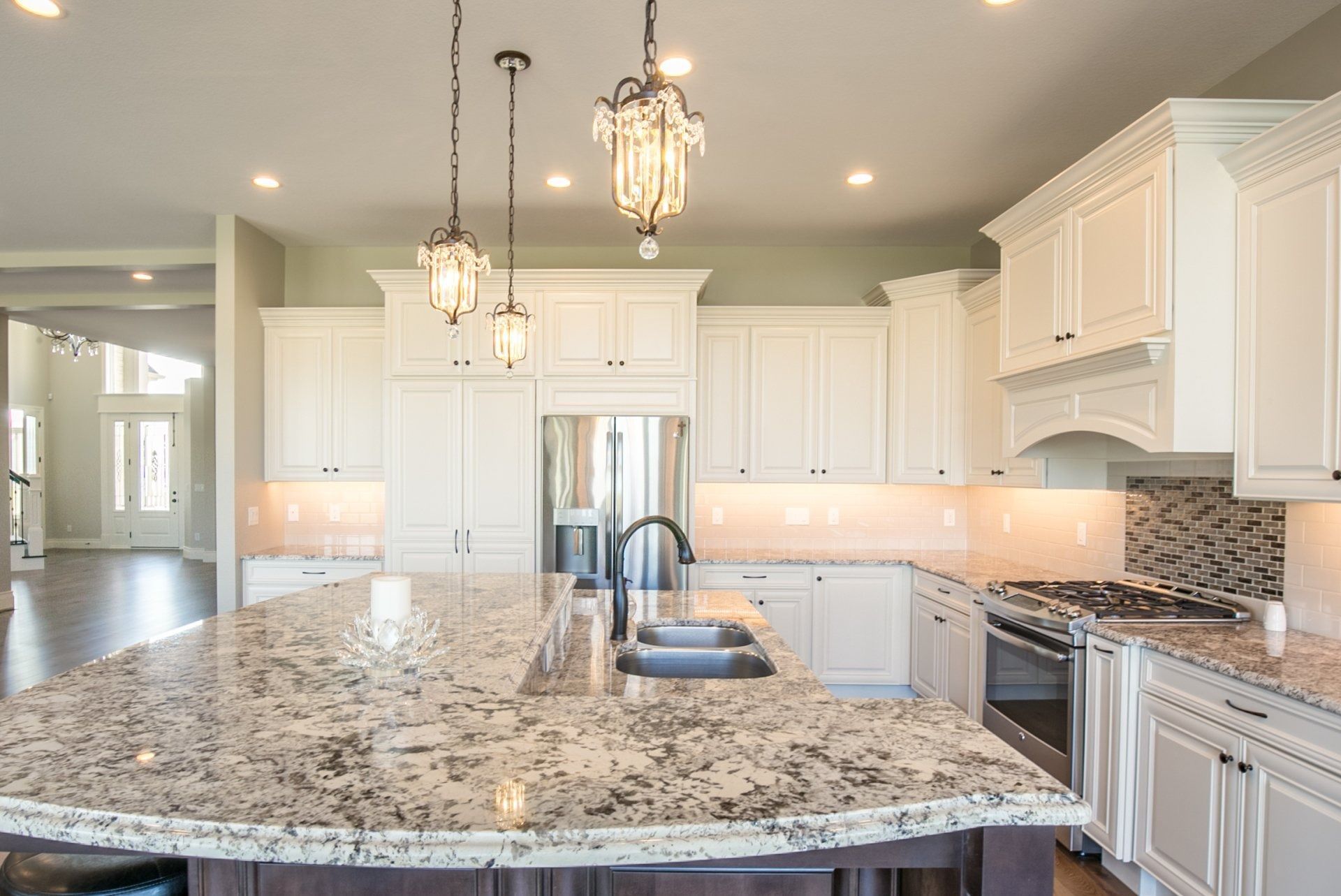 Bright kitchen with white cabinets, granite countertops, and stainless steel appliances.