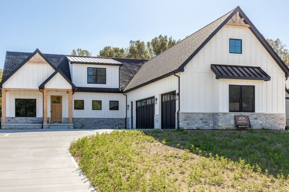 Modern white farmhouse with black trim, gray stone, and a two-car garage.