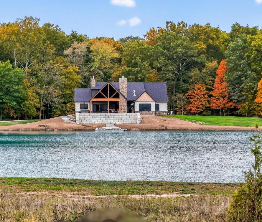 House by a lake surrounded by autumn trees.