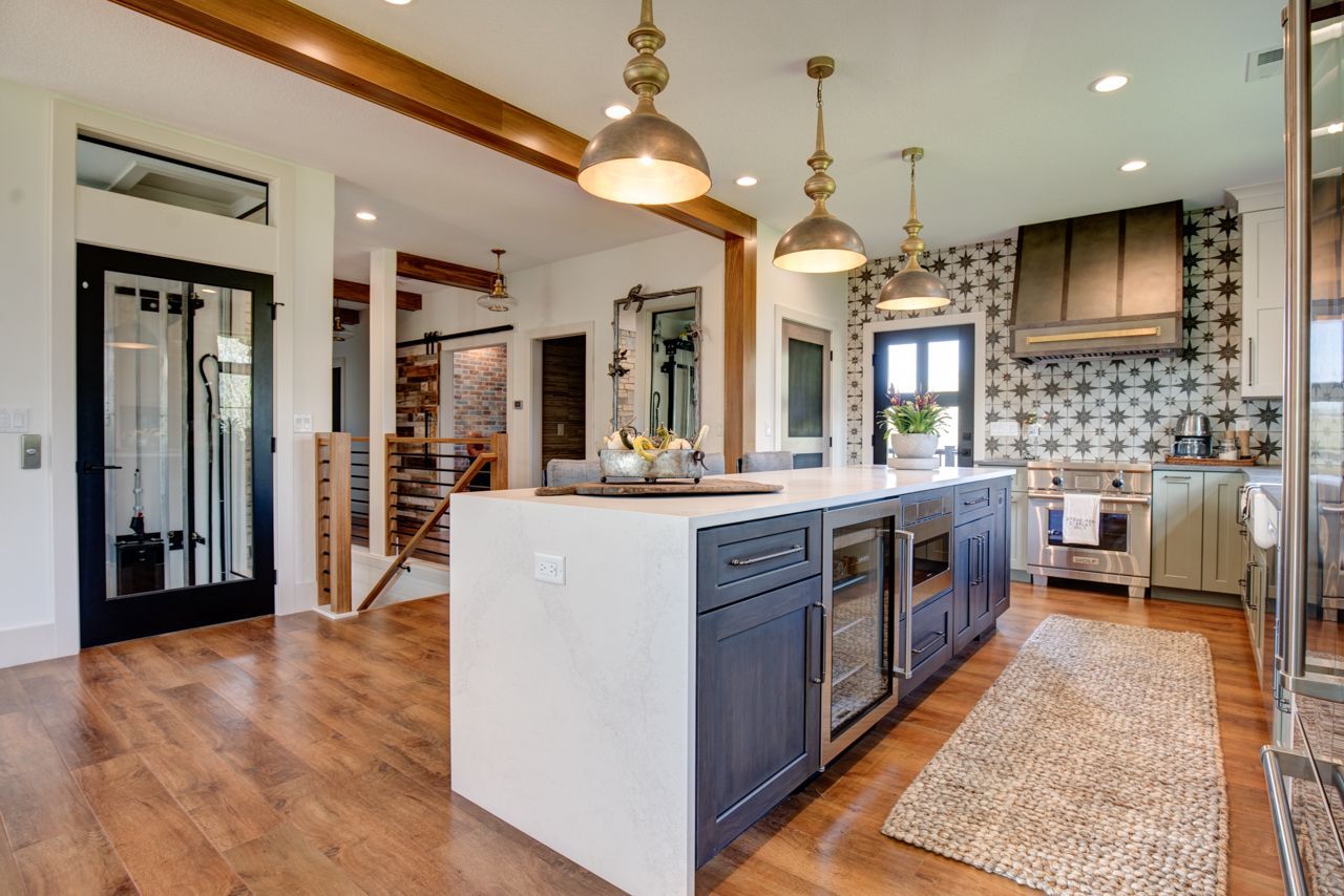 Spacious kitchen with island, wooden floors, and pendant lights. Cabinets are blue and white.