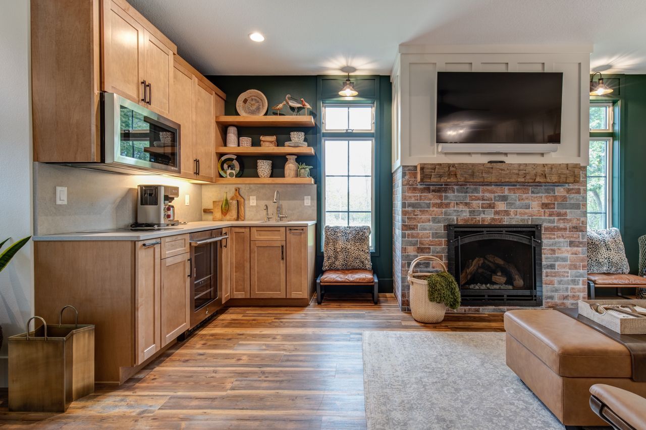 Kitchen and living room with fireplace, cabinets, and wood flooring; dark green wall accent.