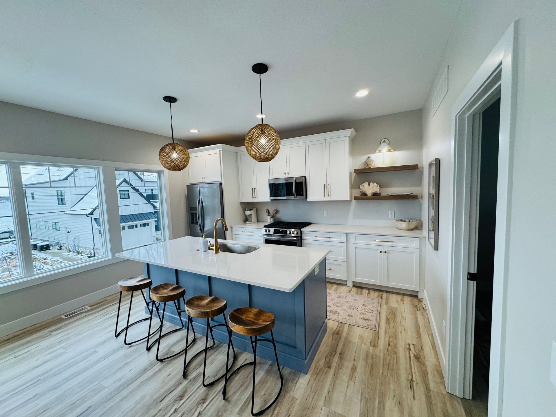 Modern kitchen with blue island, white cabinets, and wooden stools.