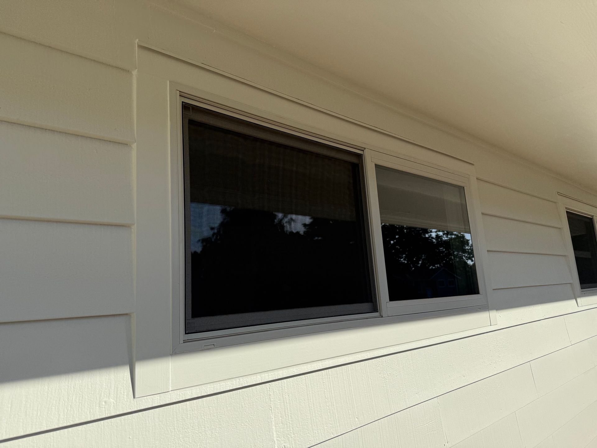 White house exterior with windows, some covered by dark shades.