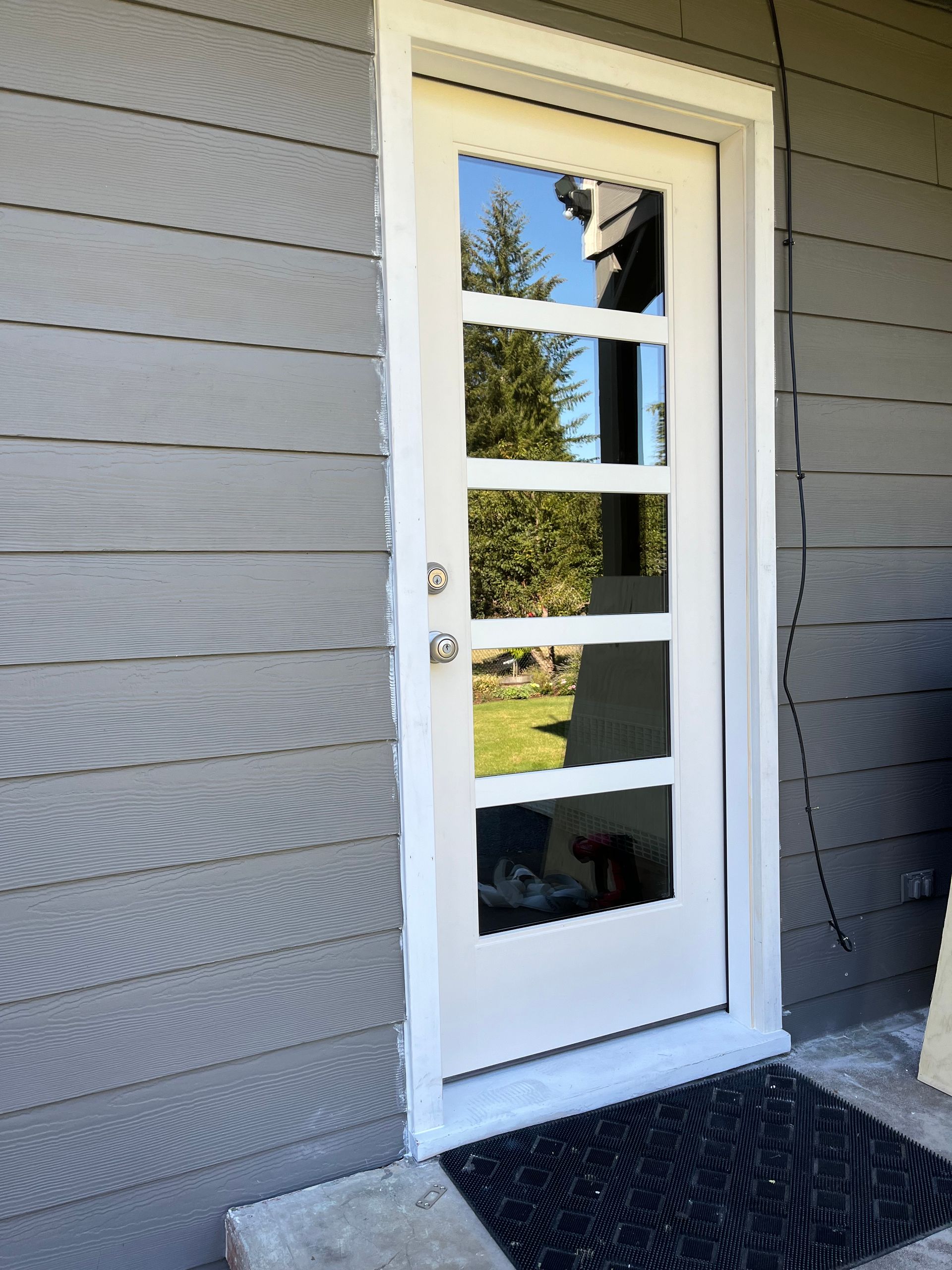 Yellow level resting on a windowsill, measuring the window's alignment. Window frame, house visible through the glass.