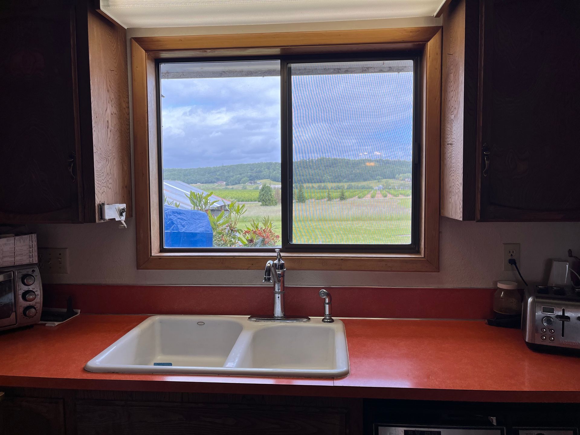 White-framed, two-pane sliding window installed on a teal-sided house, showing FlexWrap underneath.