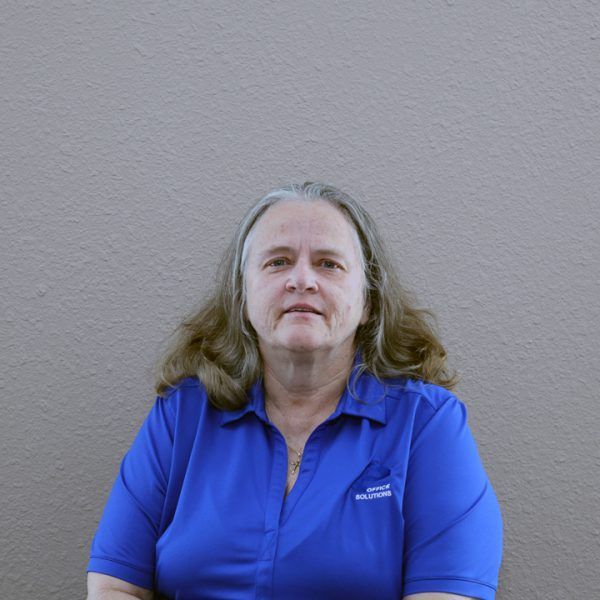 A woman in a blue shirt is sitting in front of a wall