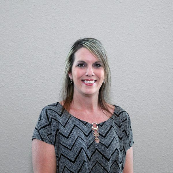 A woman in a gray and black chevron shirt is smiling for the camera.