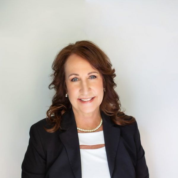 A woman wearing a black jacket and white shirt smiles for the camera