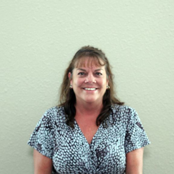 A woman in a blue and white shirt is smiling for the camera