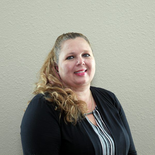 A woman in a black jacket and striped shirt is smiling for the camera.