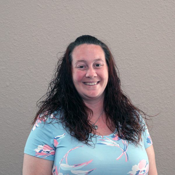 A woman in a blue floral shirt is smiling for the camera.