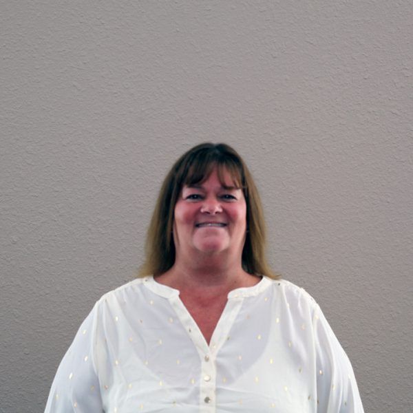 A woman in a white shirt is smiling for the camera