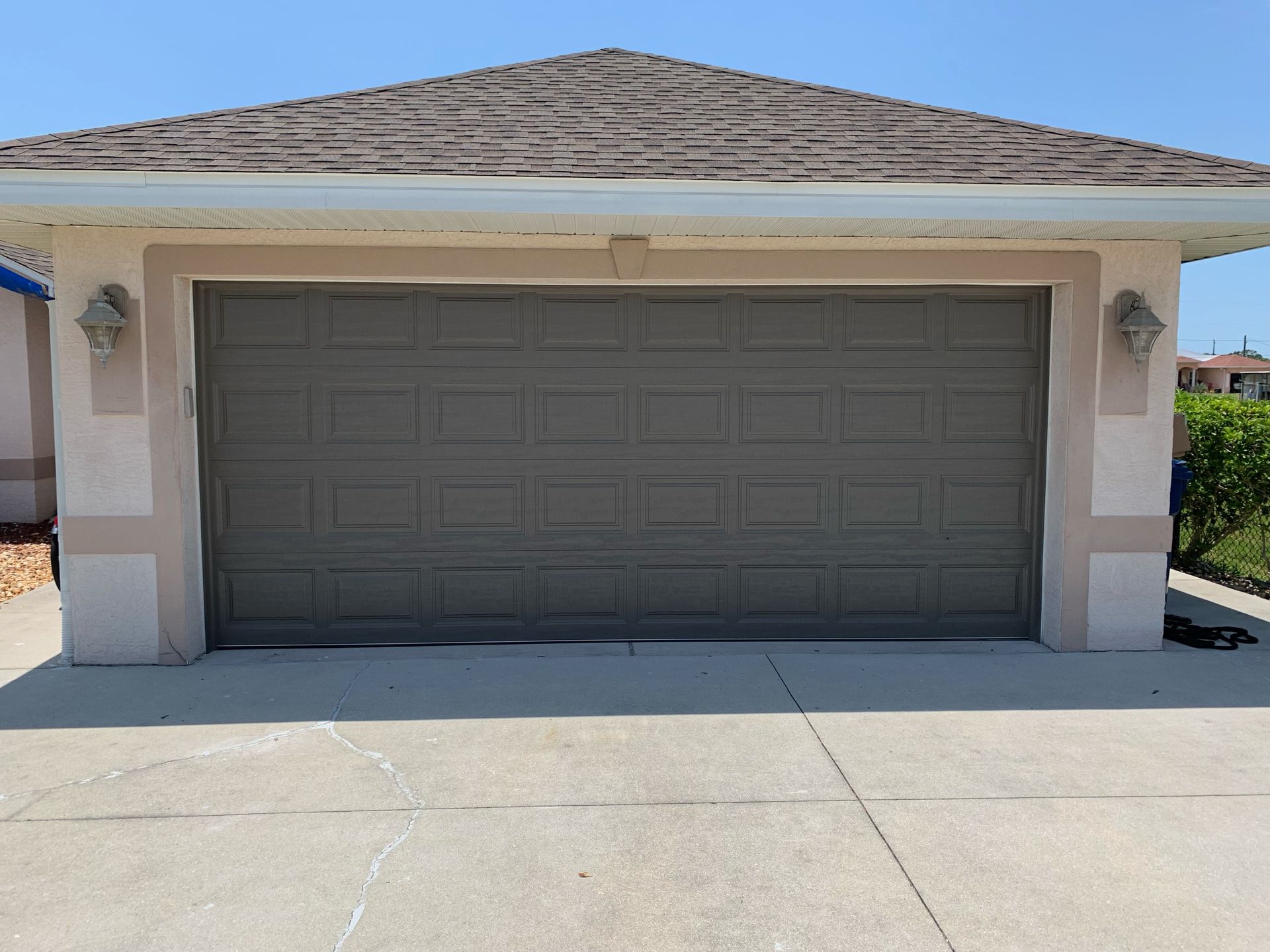 A gray garage door is sitting in front of a house.