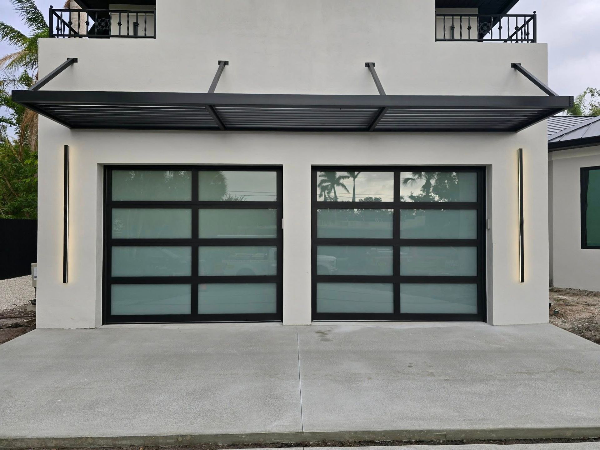 A white house with a black garage door and a canopy.