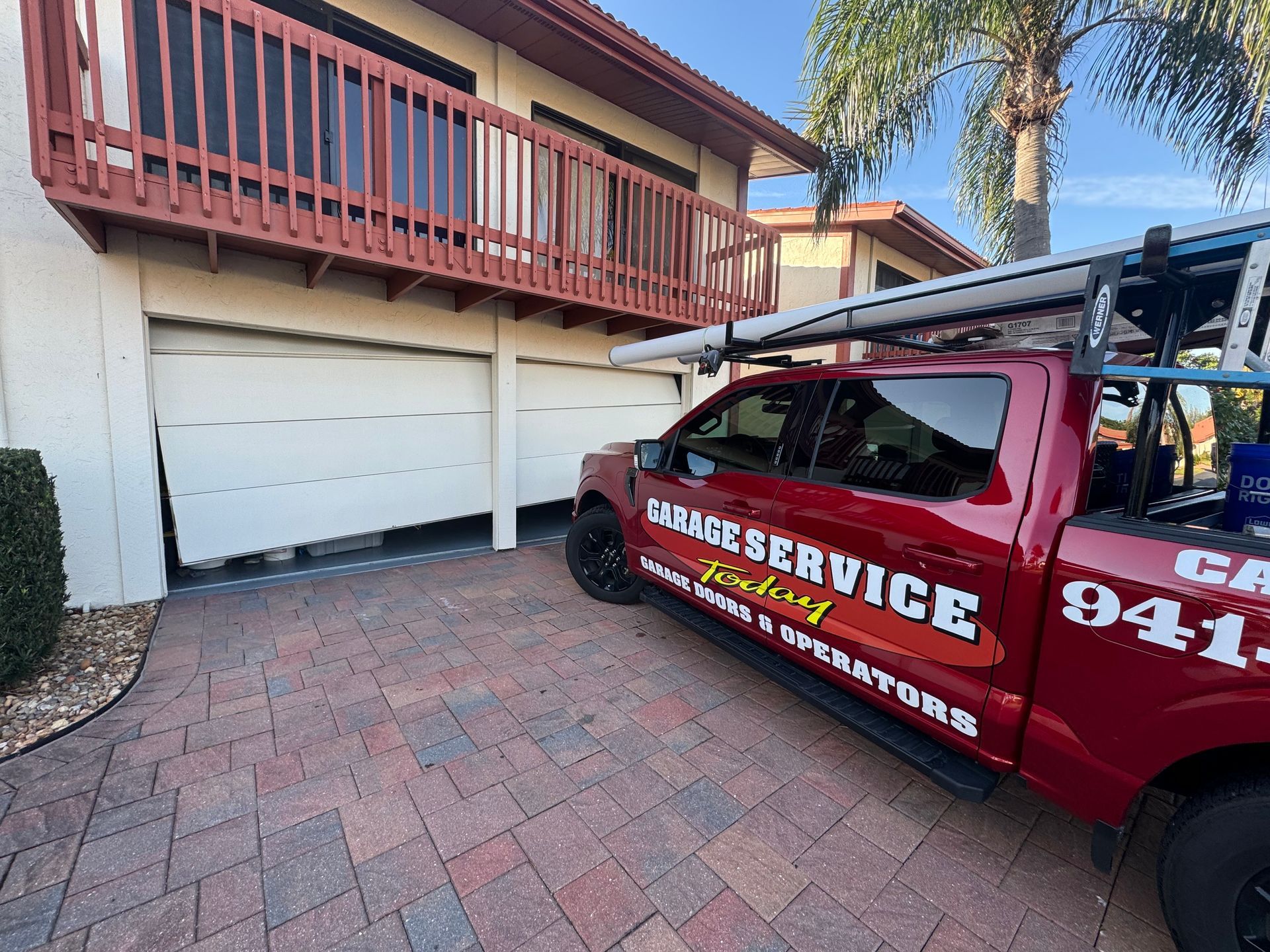 A red garage service truck is parked in front of a house.