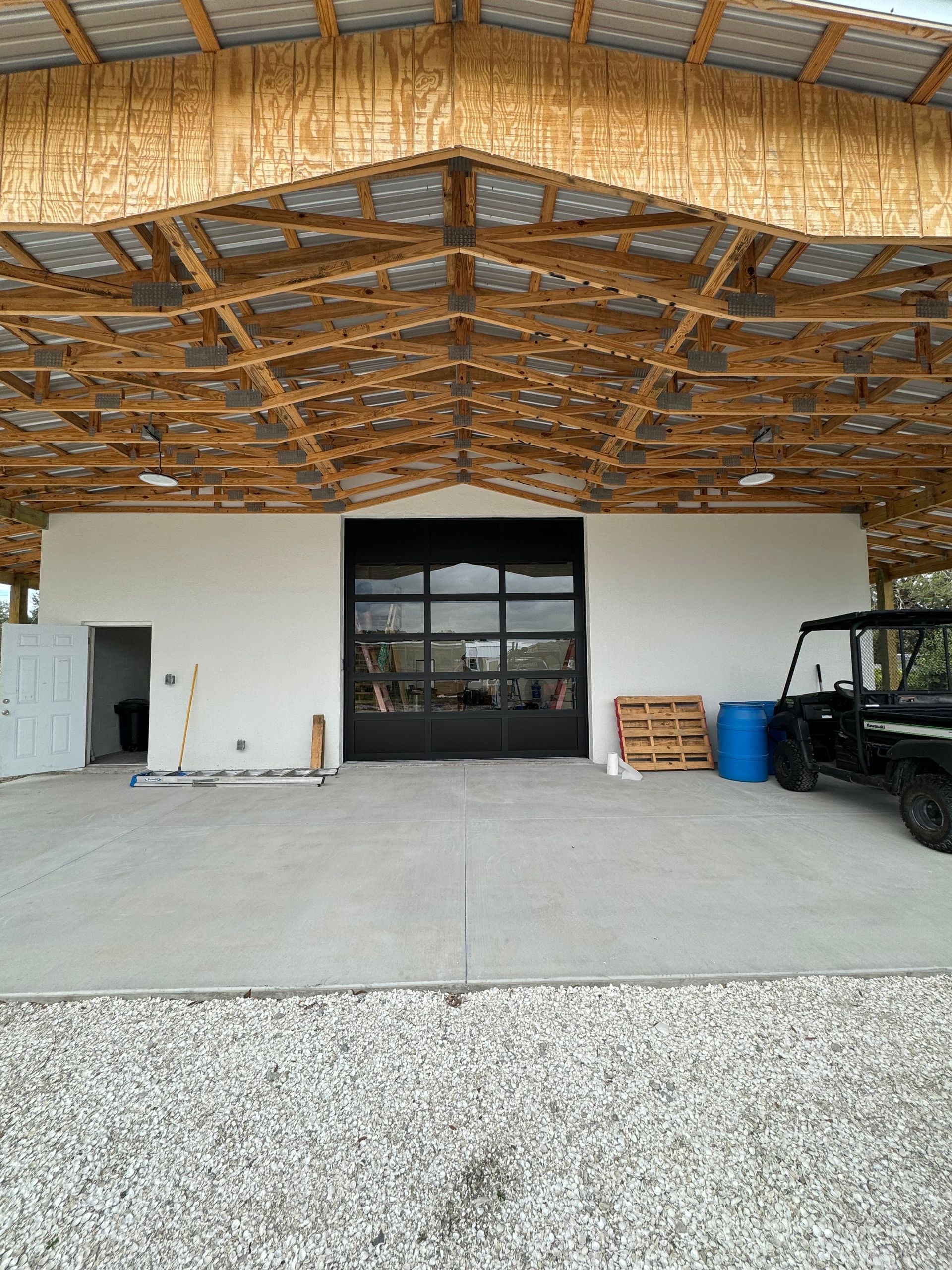 A white building with a black door and a black vehicle parked underneath it.