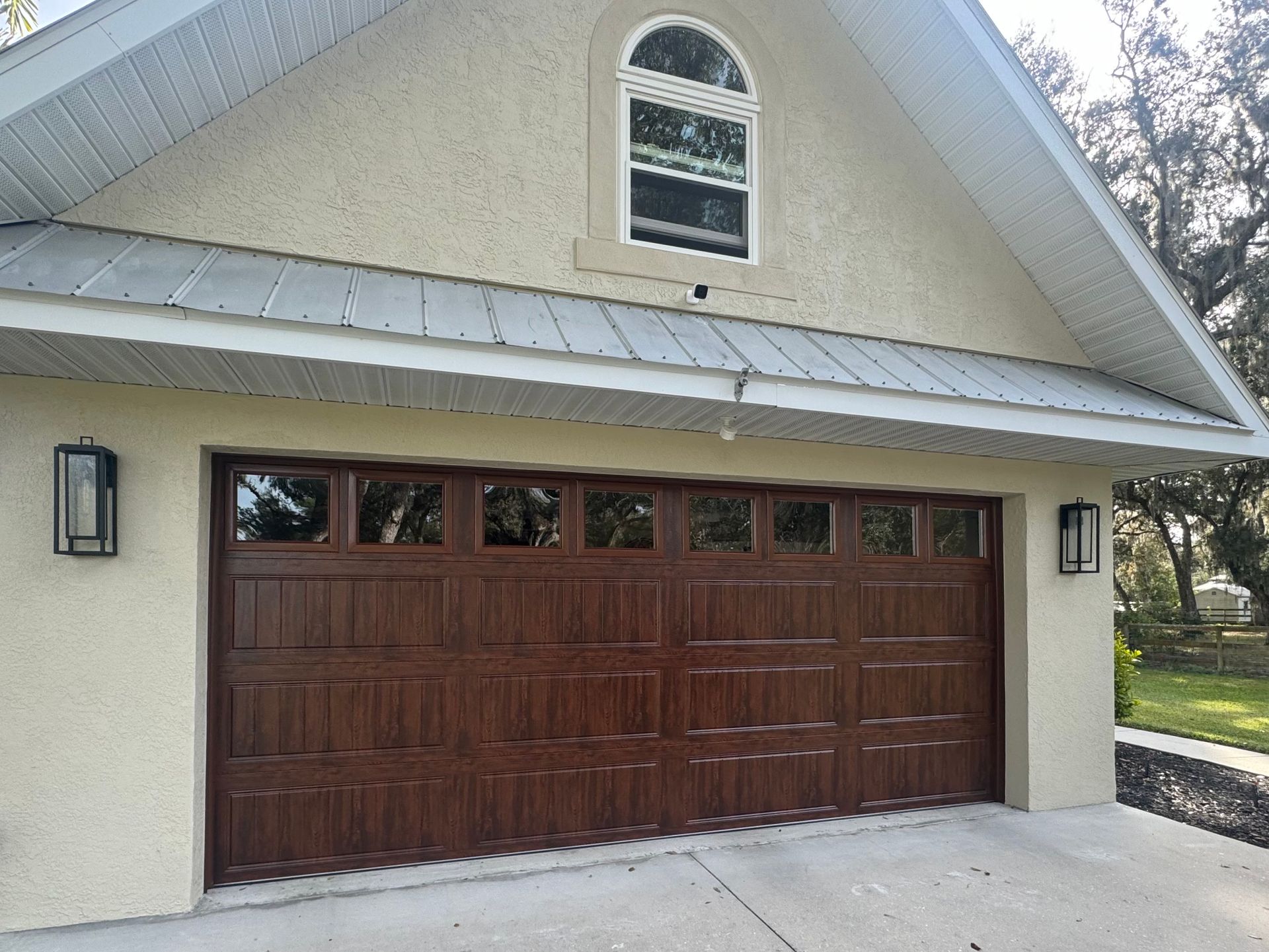 A large brown garage door is on the side of a house.