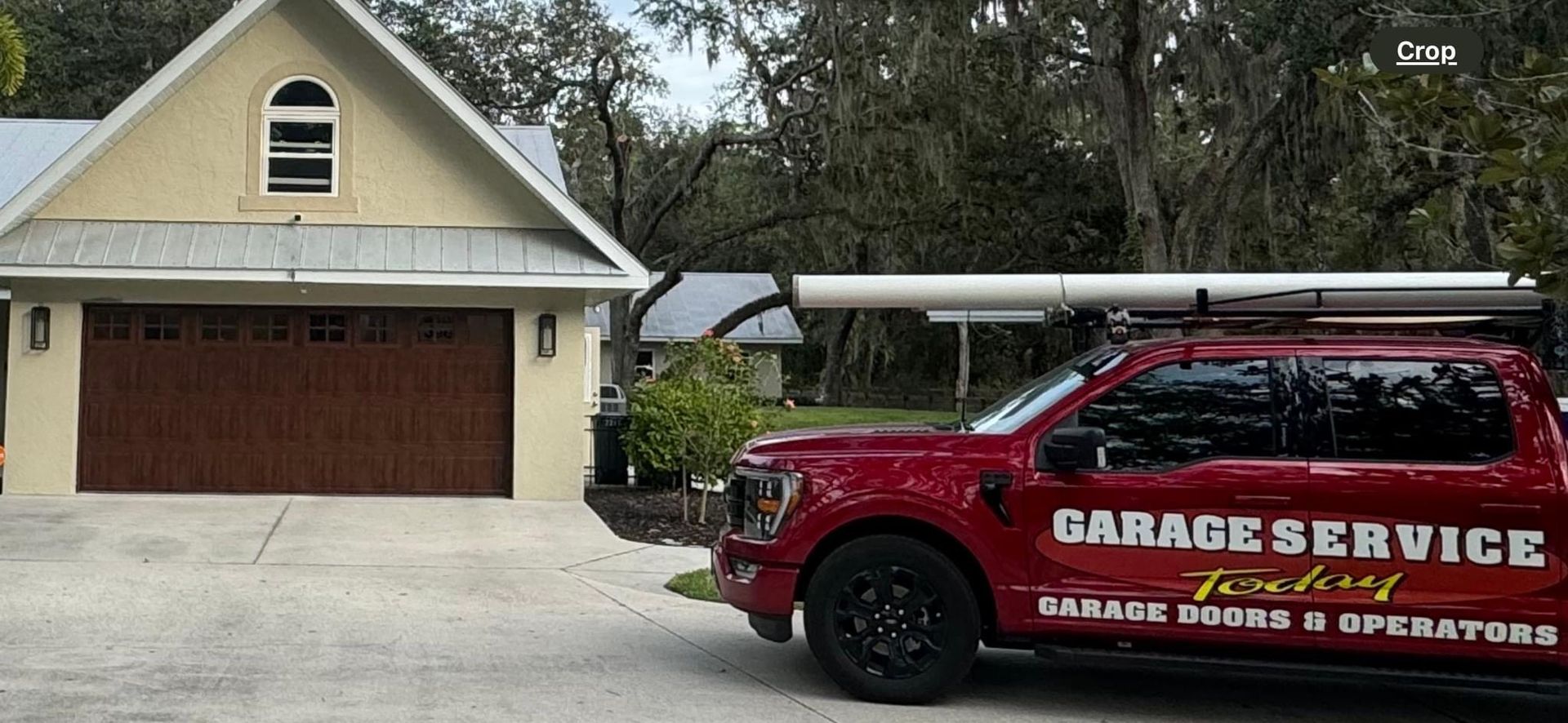 A red garage service truck is parked in front of a house.