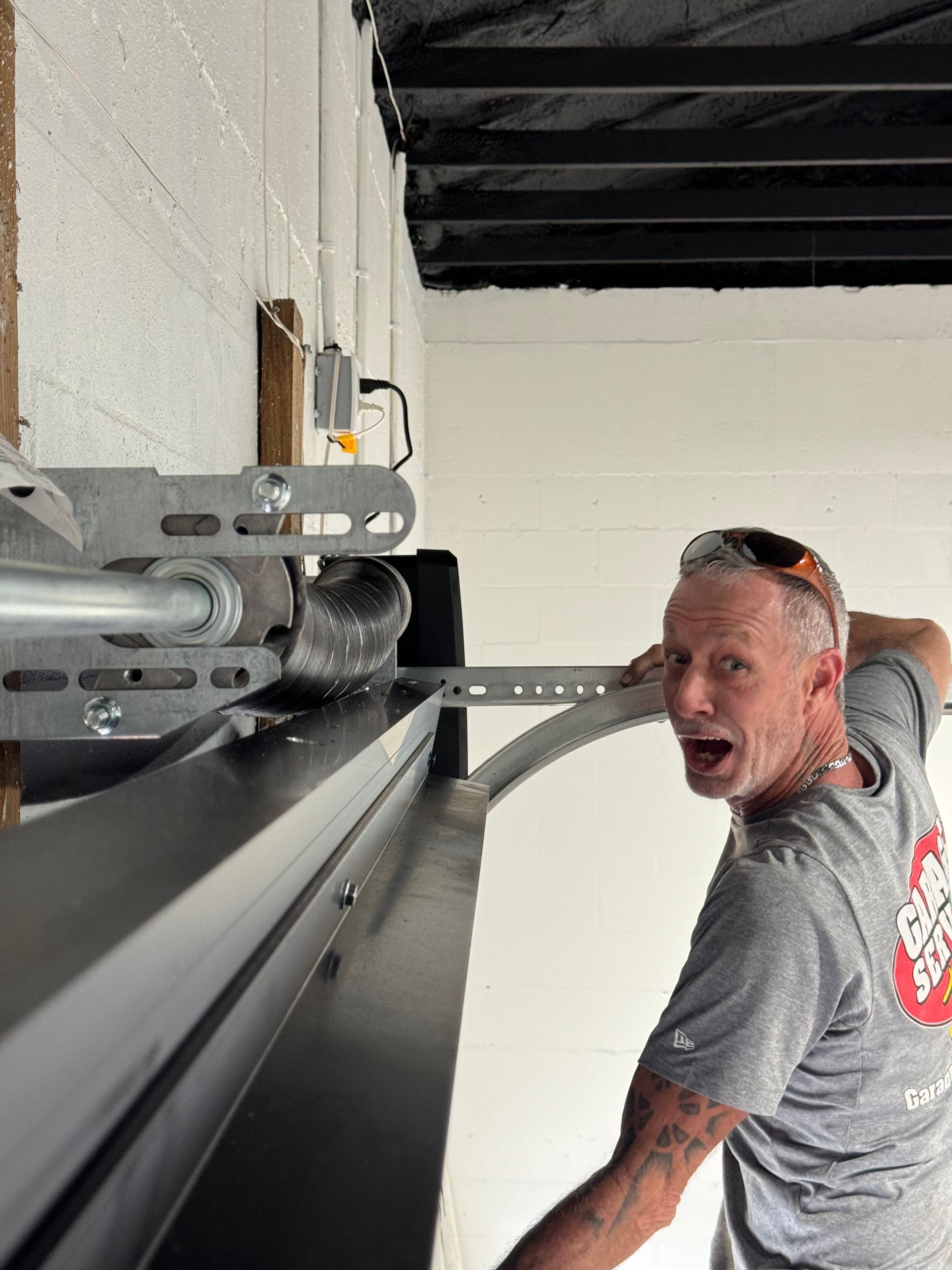 A man is working on a garage door in a garage.
