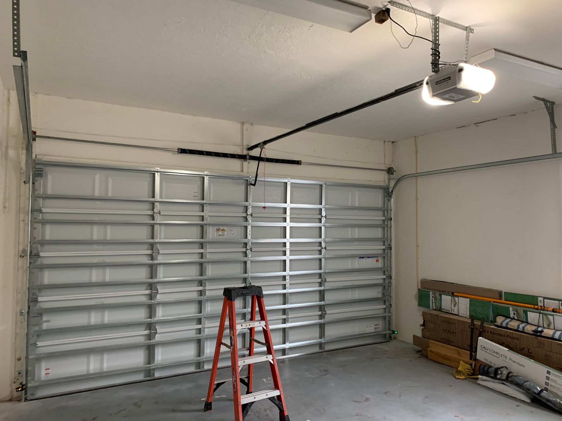A garage with a ladder and a garage door opener.