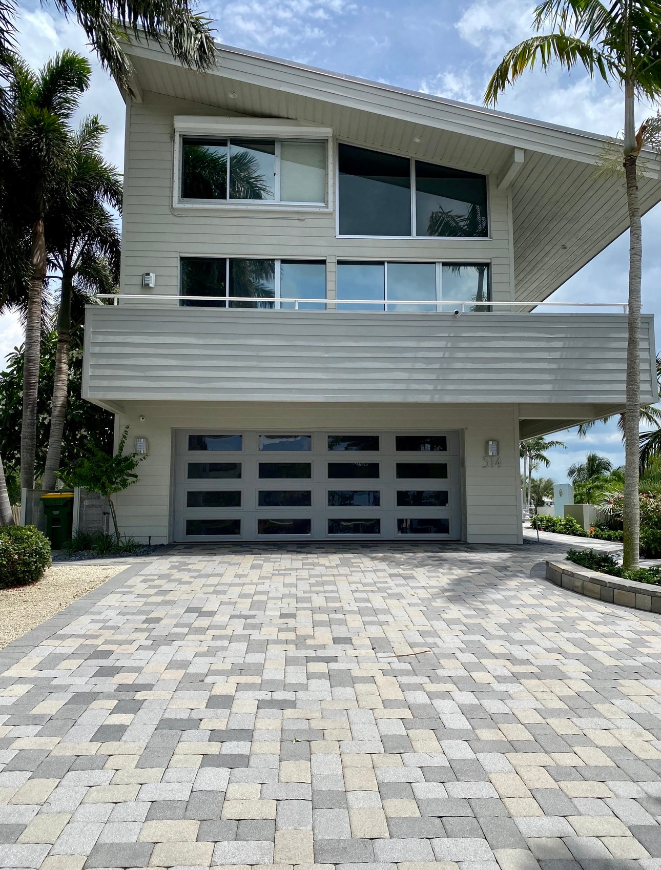 A large white house with a brick driveway in front of it