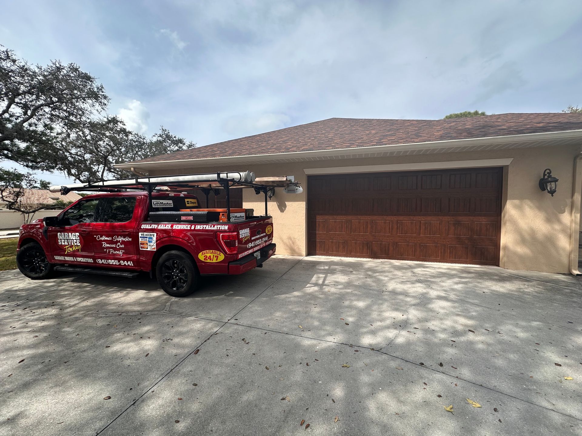 A red truck is parked in front of a garage door.