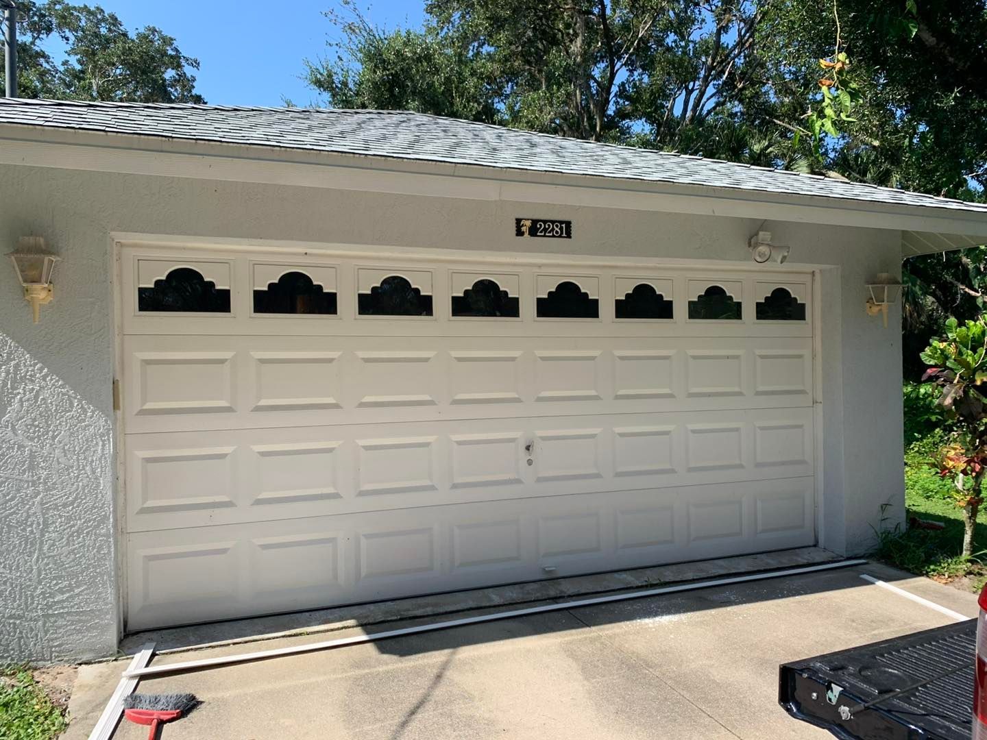 A white garage door with a roof and a truck parked in front of it.