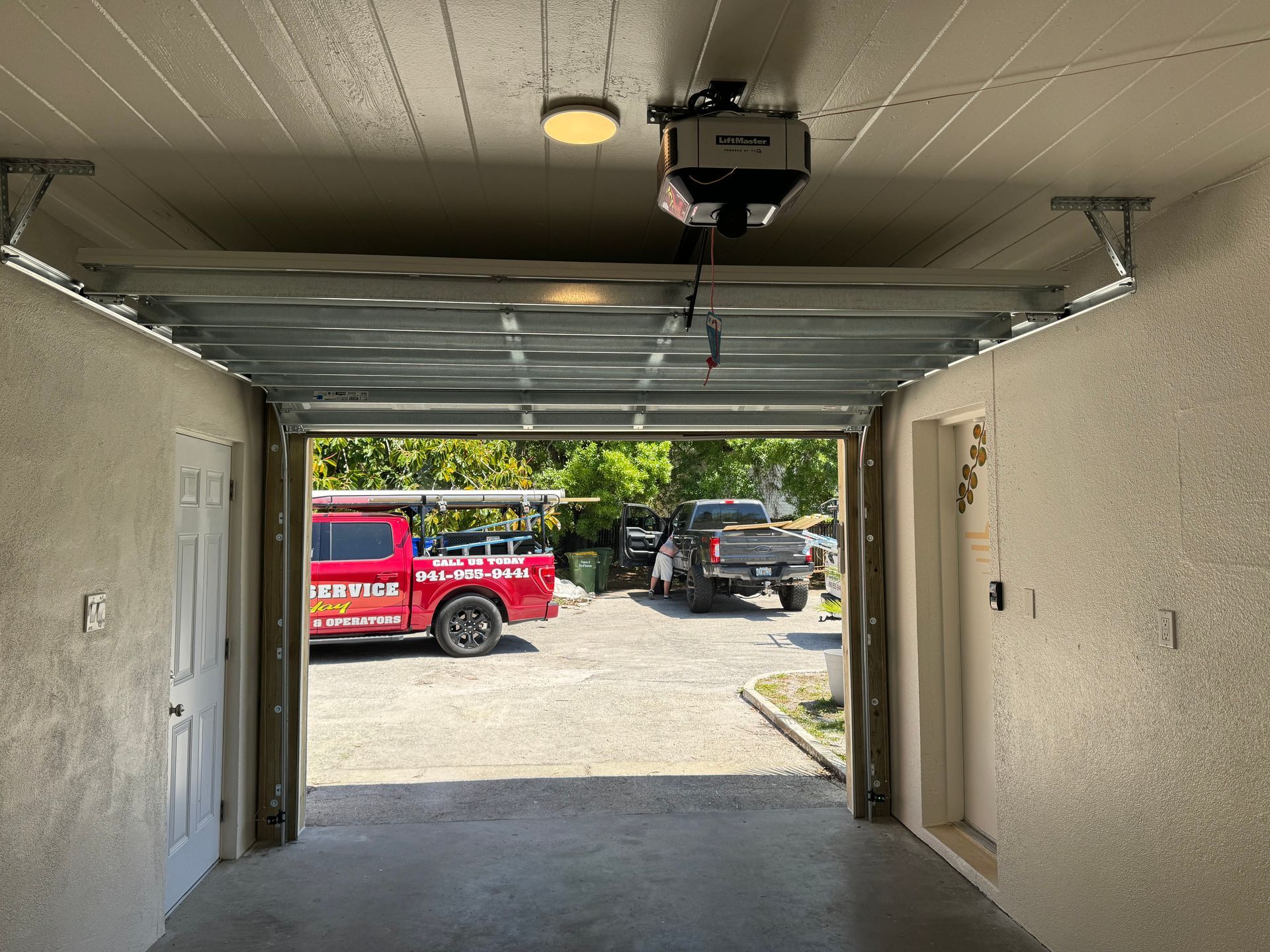 A red truck is parked in a garage with the door open.