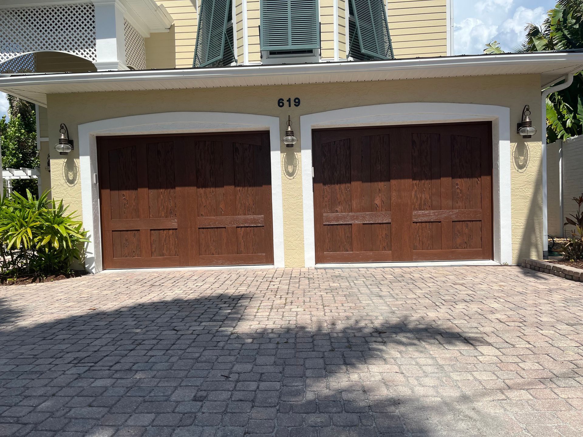 A house with two brown garage doors and a brick driveway