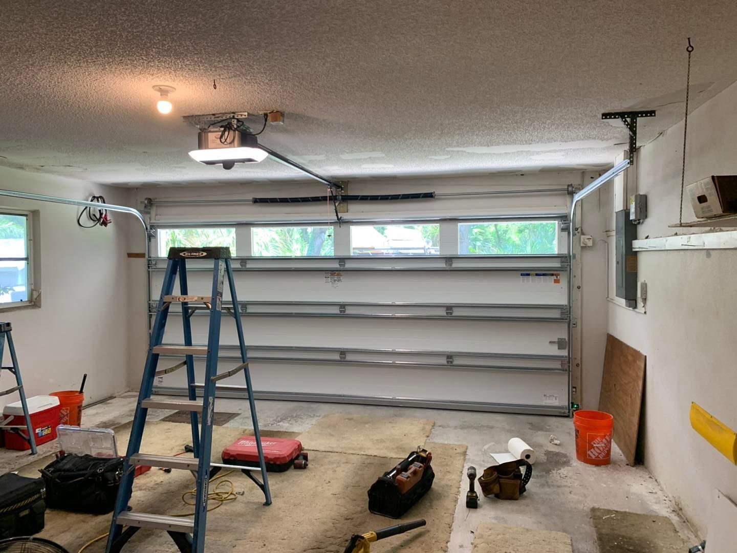 A garage with a garage door open and a ladder in it.