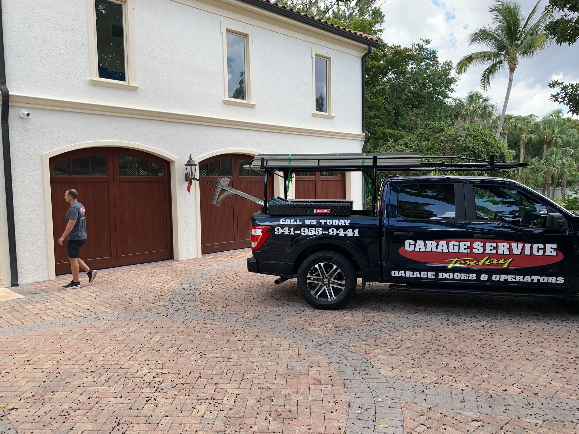 A garage service truck is parked in front of a house.