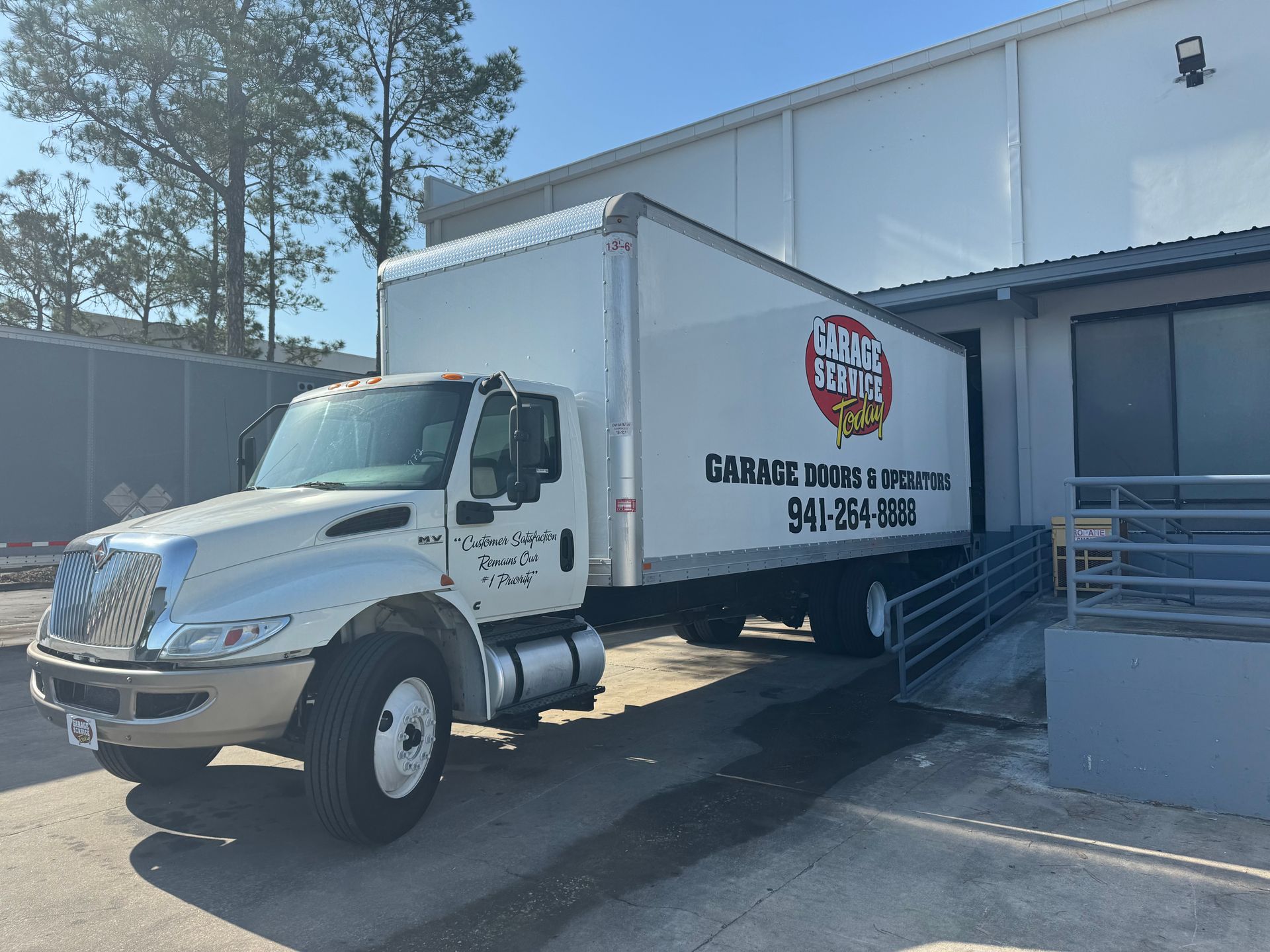 A white moving truck is parked in front of a building.