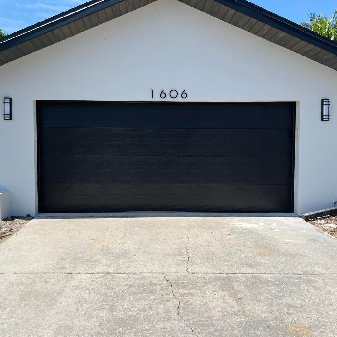 A white house with a black garage door and the address 1606