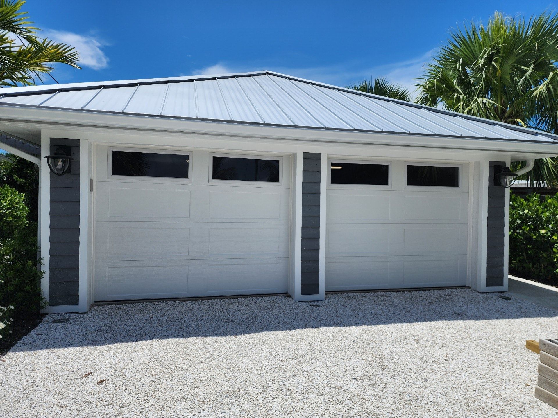 A garage with two white garage doors and a metal roof
