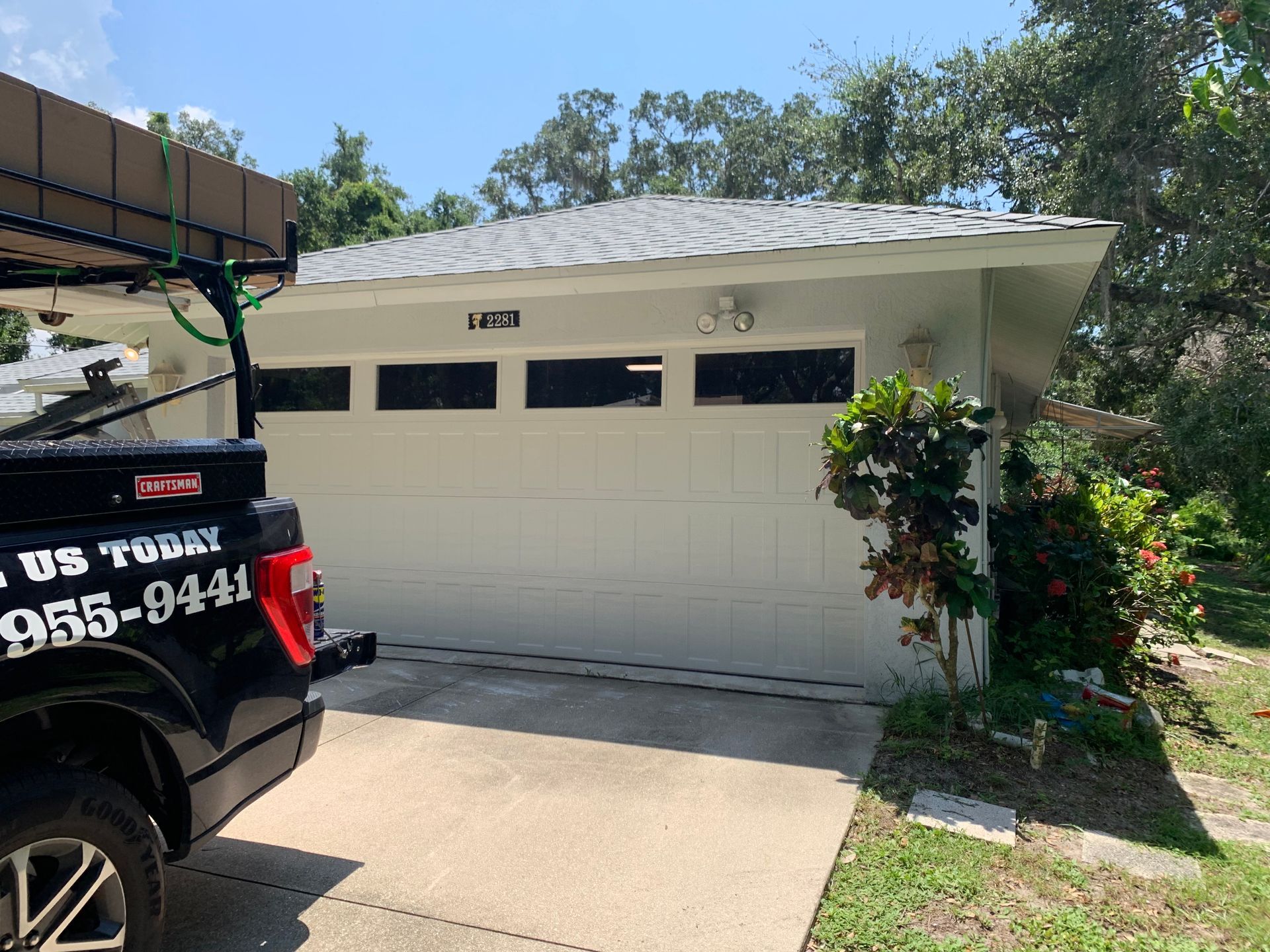 A black truck is parked in front of a white garage door.