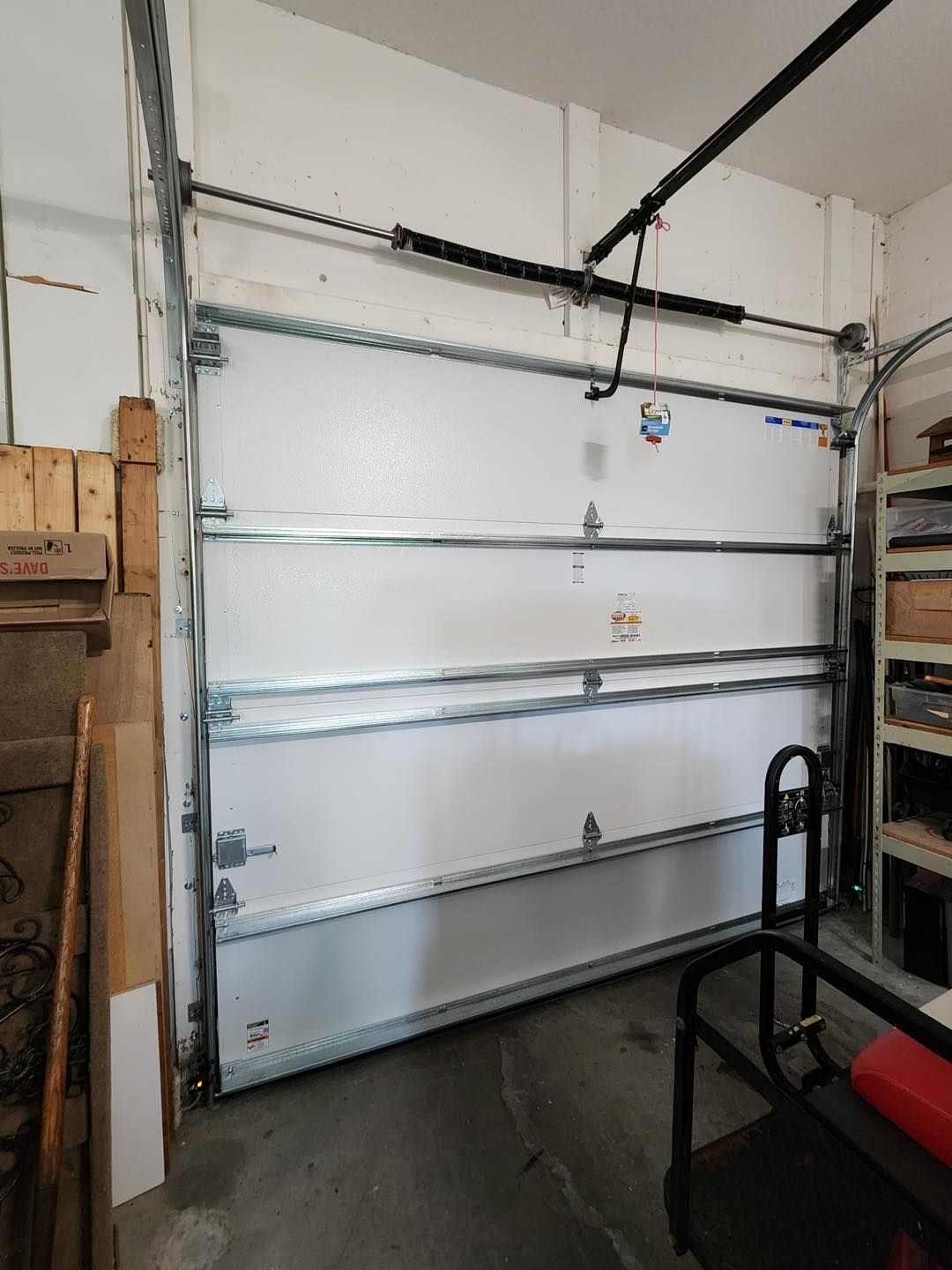 A white garage door is open in a garage.