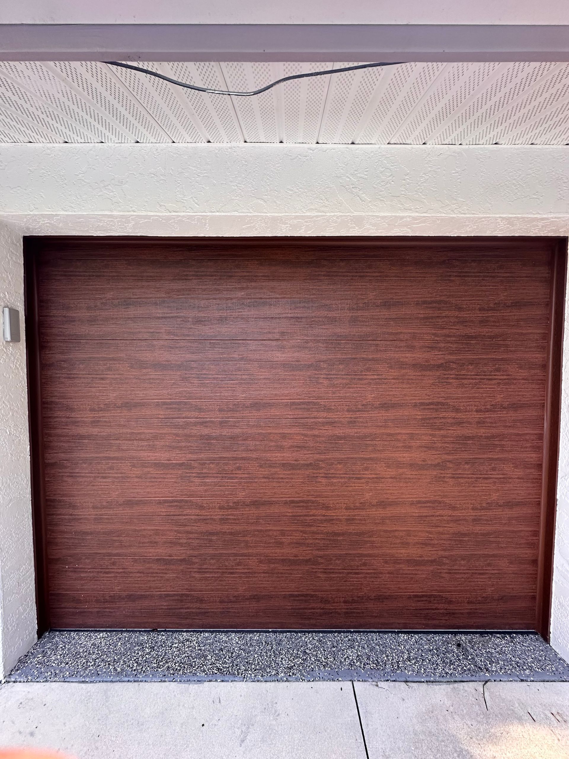 A brown garage door with a white wall behind it
