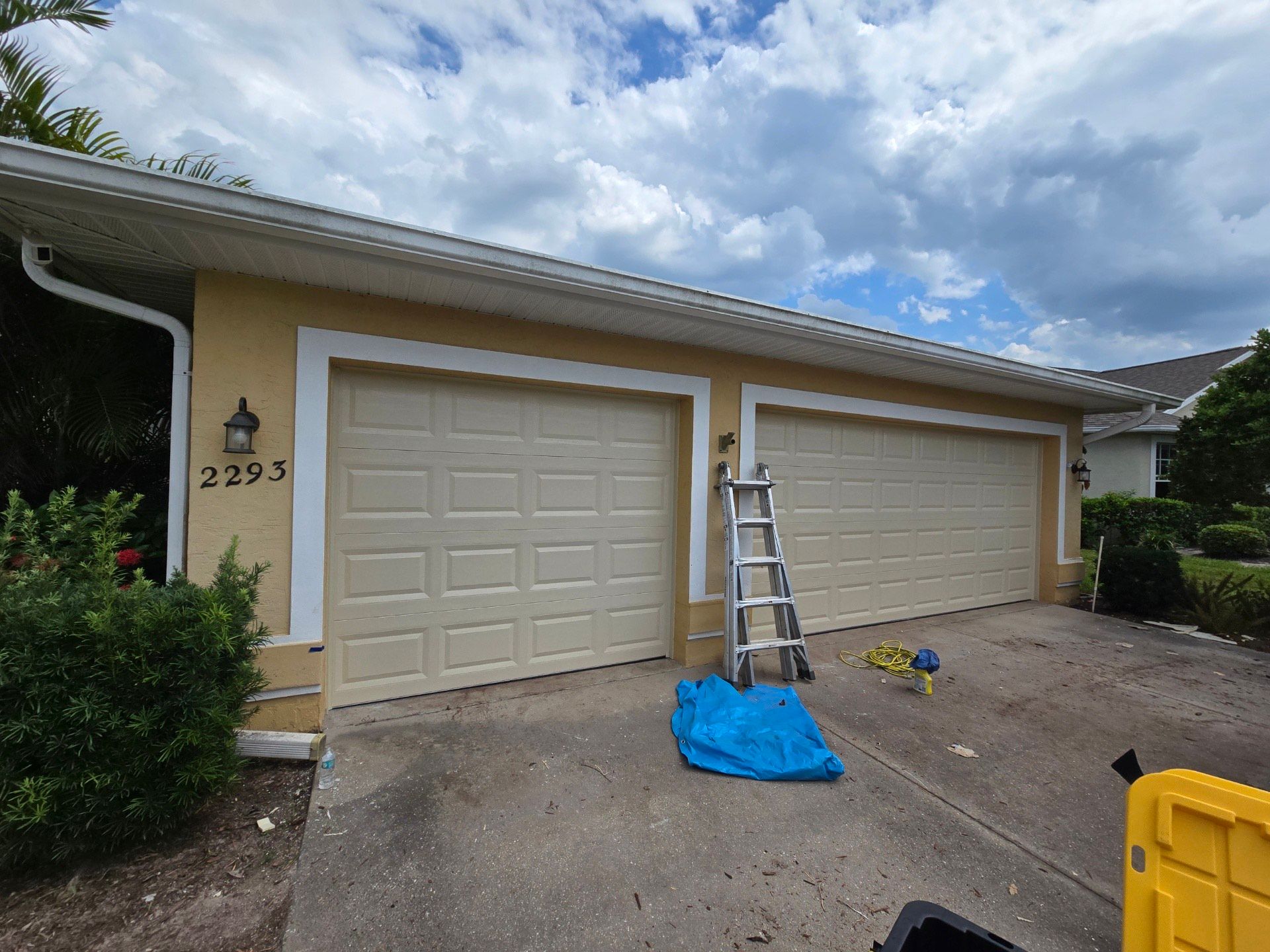 A garage door is being painted in front of a house.