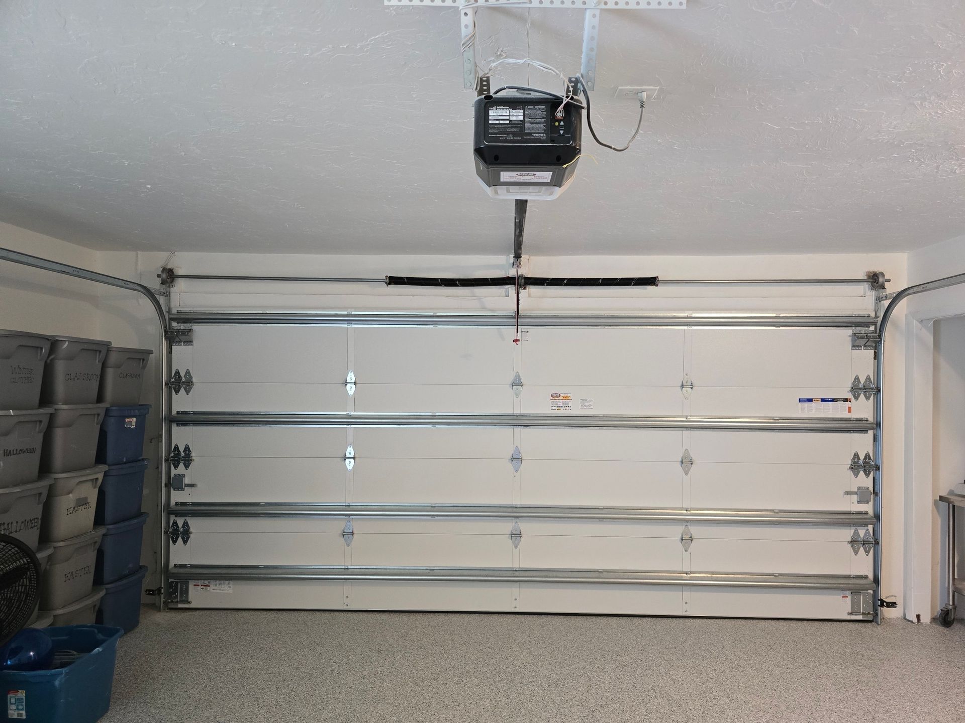 A garage with a garage door open and a ceiling lift