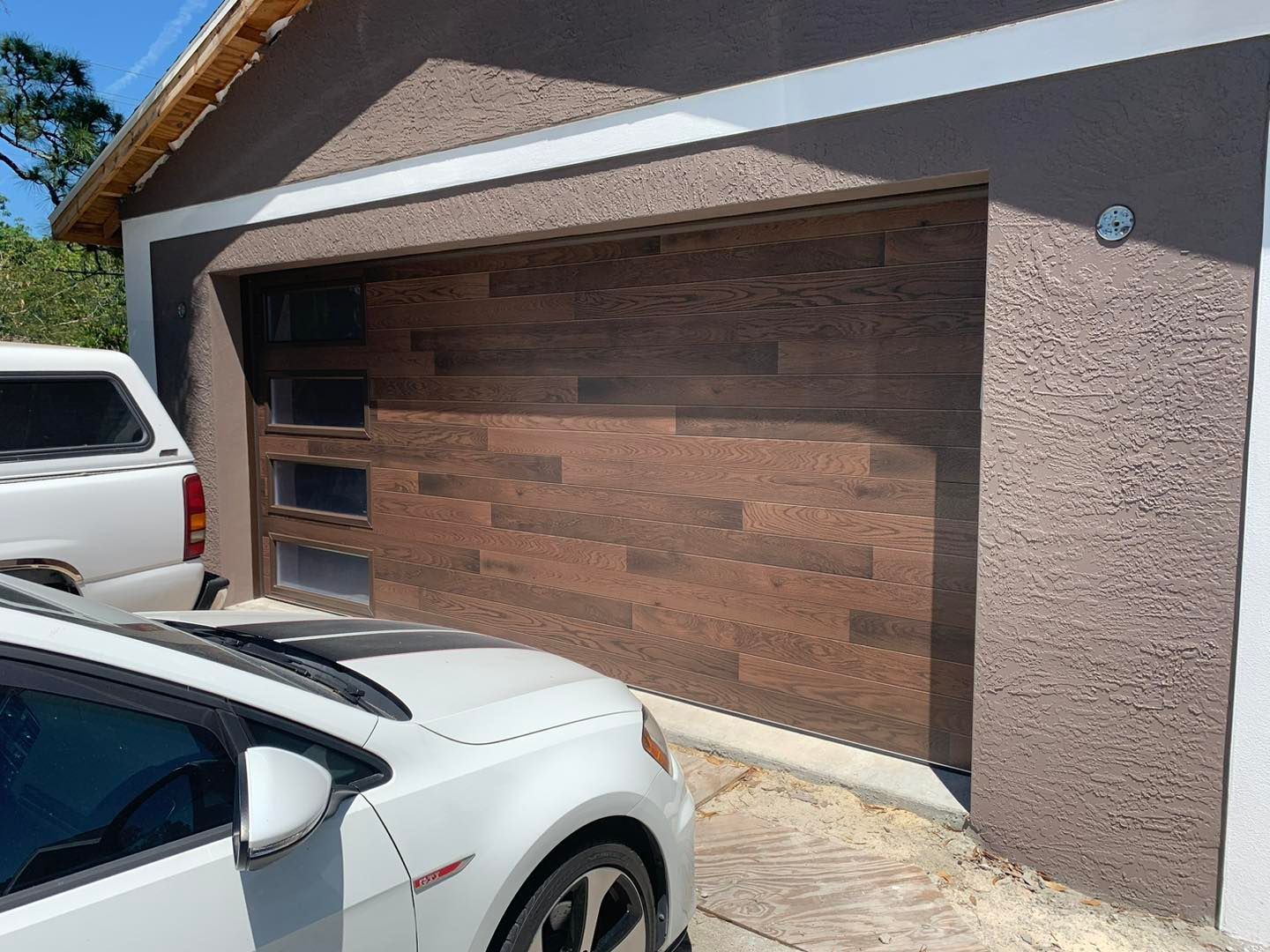 A white car is parked in front of a garage door.