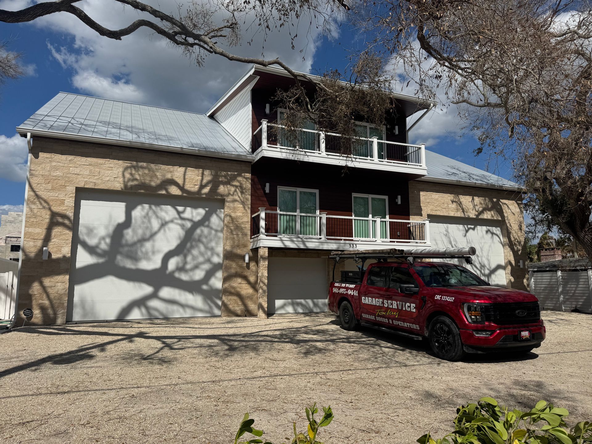 A red truck is parked in front of a large house.