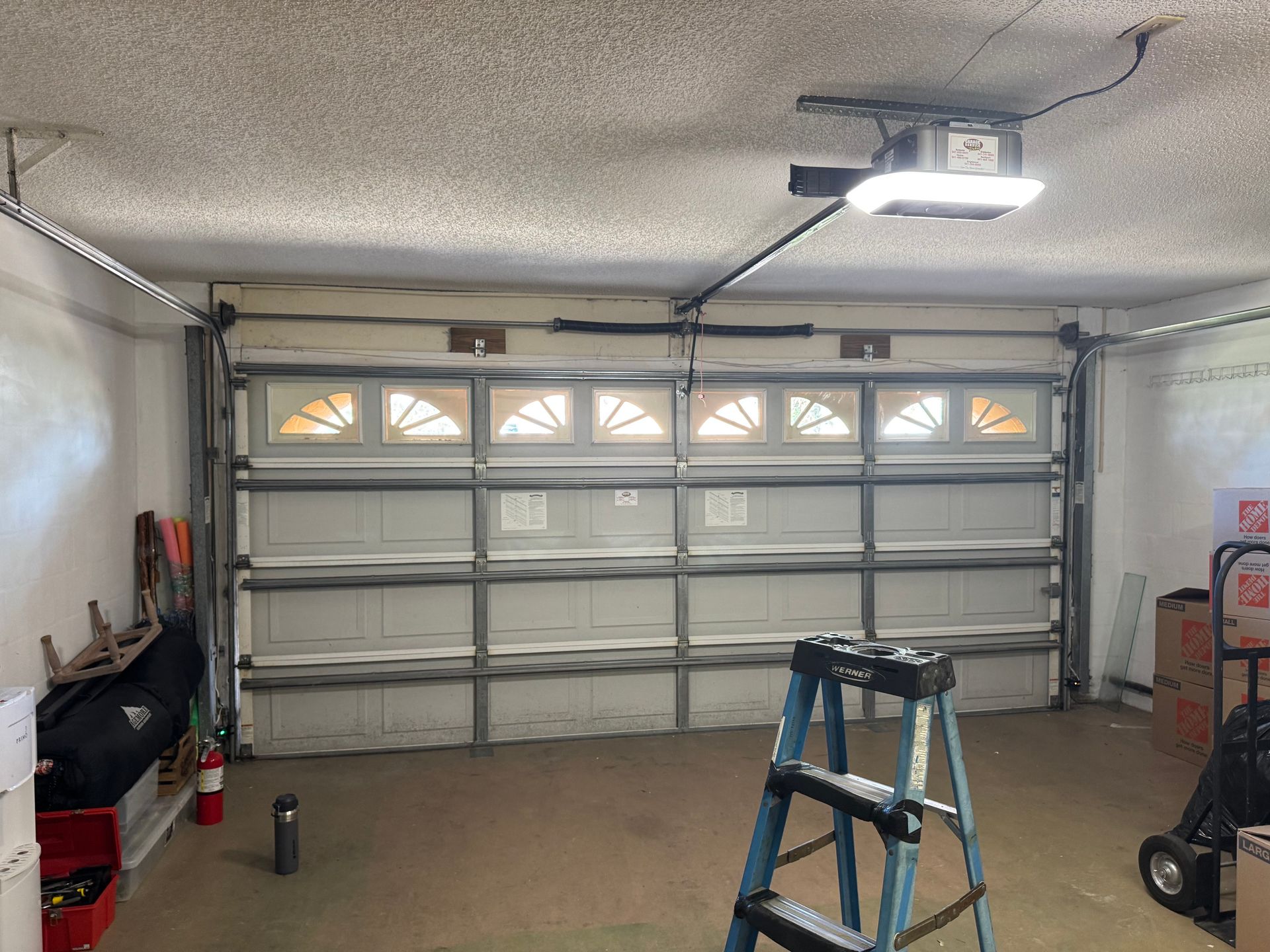 A garage with a ladder and a garage door open.