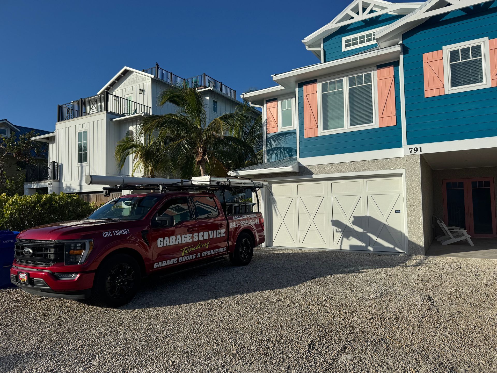 A red truck is parked in front of a blue and white house.