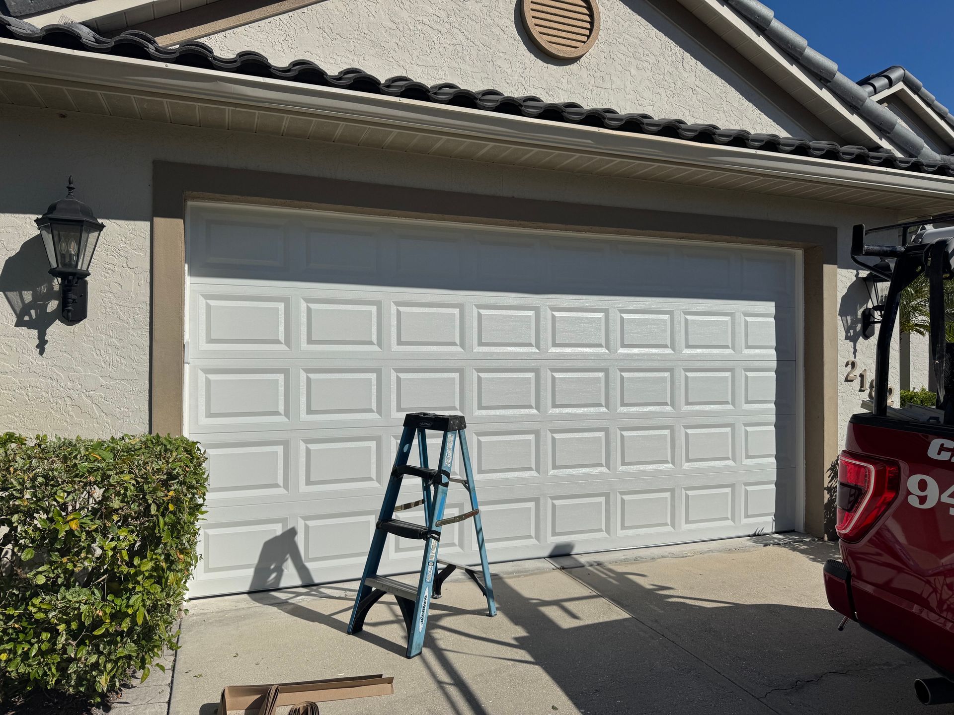 A ladder is sitting in front of a white garage door.