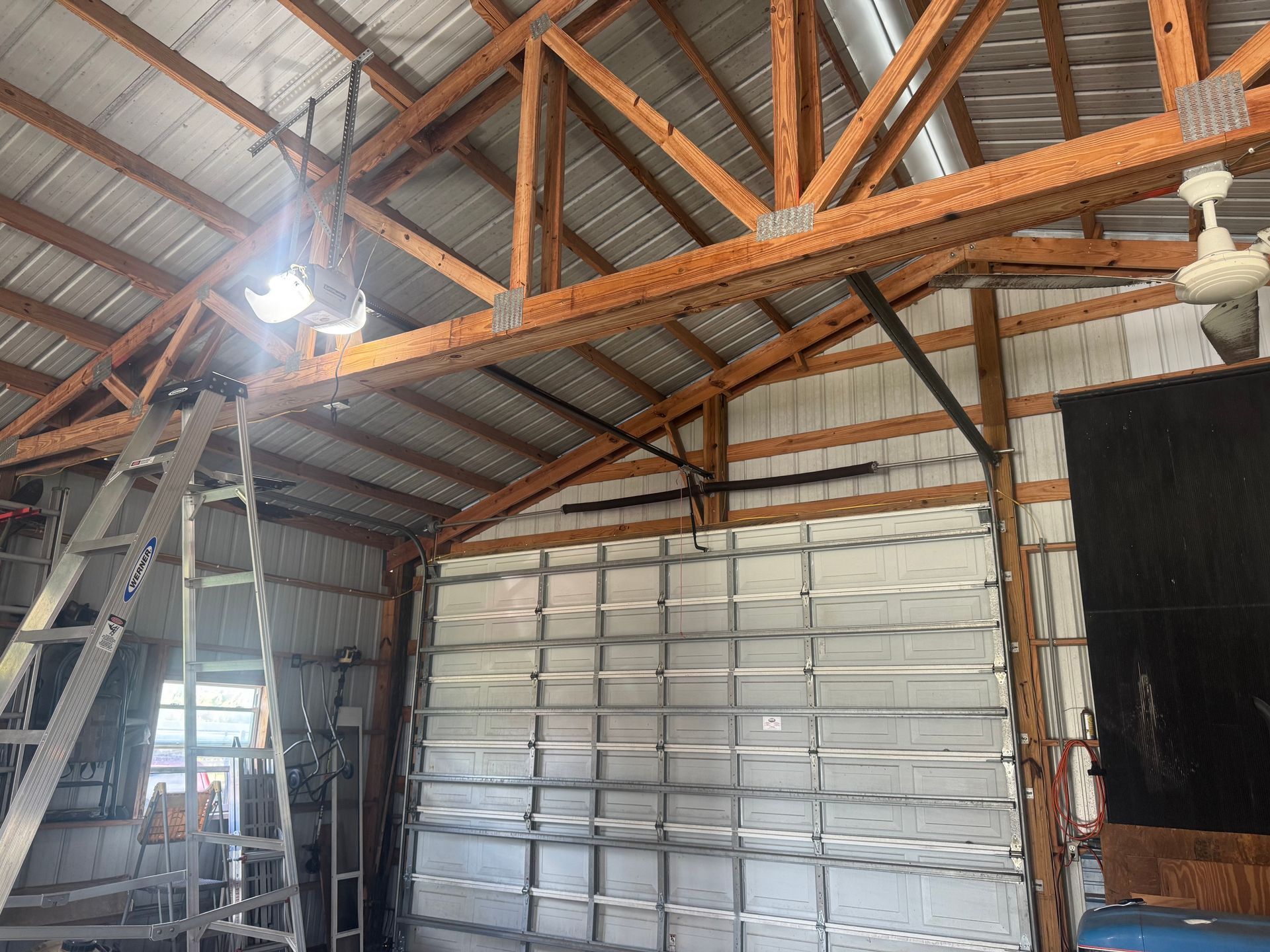 A garage with a ladder and a ceiling fan.