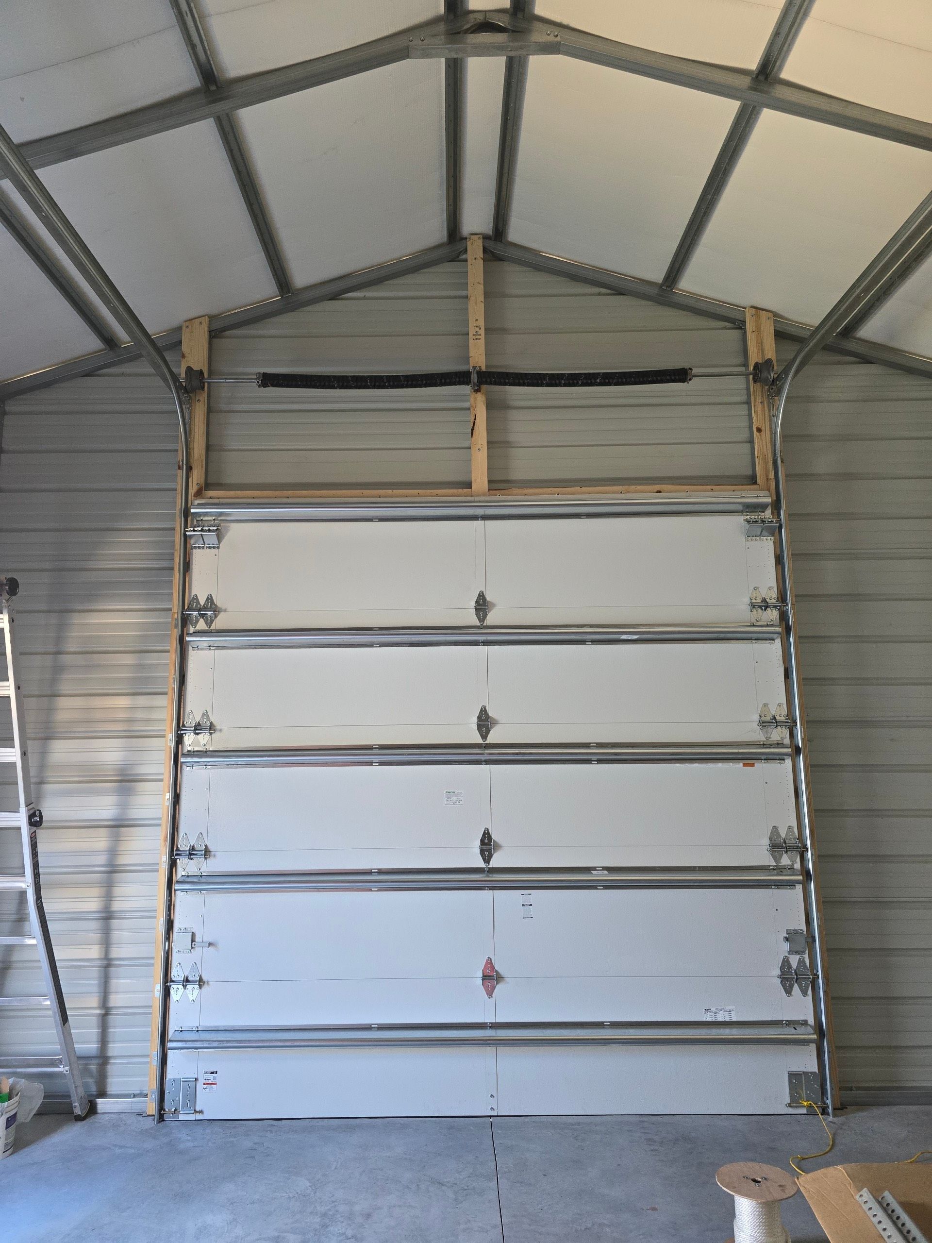A garage with a large white garage door and a ladder