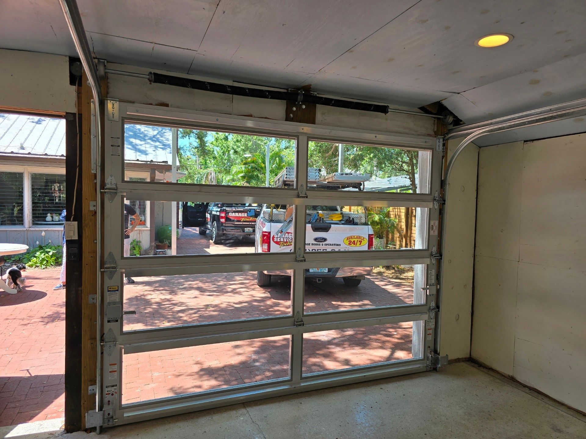 A white truck is parked in a garage with a garage door open.