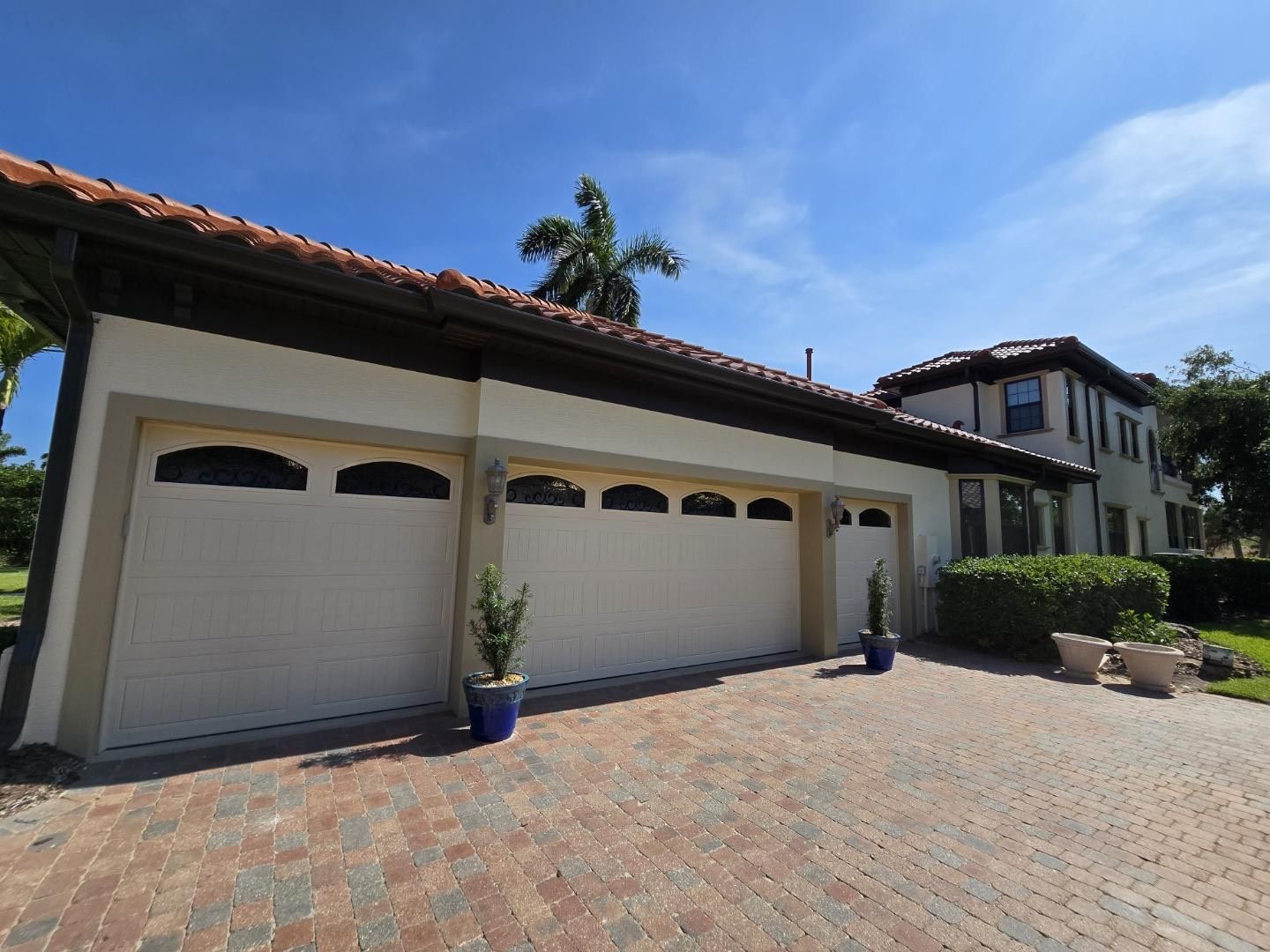 A large house with three garage doors and a brick driveway